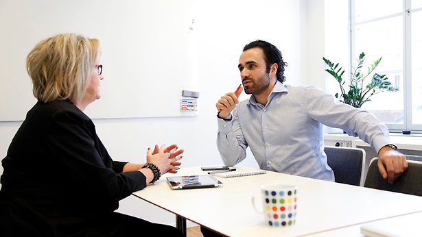 En man och en kvinna sitter på ett möte och pratar med varandra