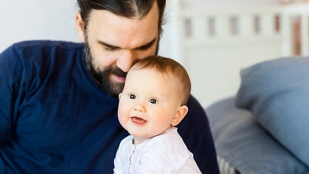 Vuxen lutar sitt huvud mot ett litet, leende barn