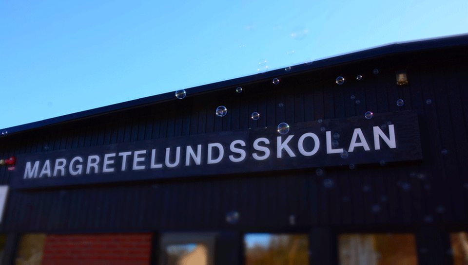 Bild på Margretelundsskolan. Röd-brun tegelbyggnad med såpbubblor framför.