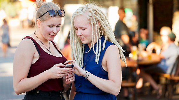 Två tonåringar tittar på en mobil