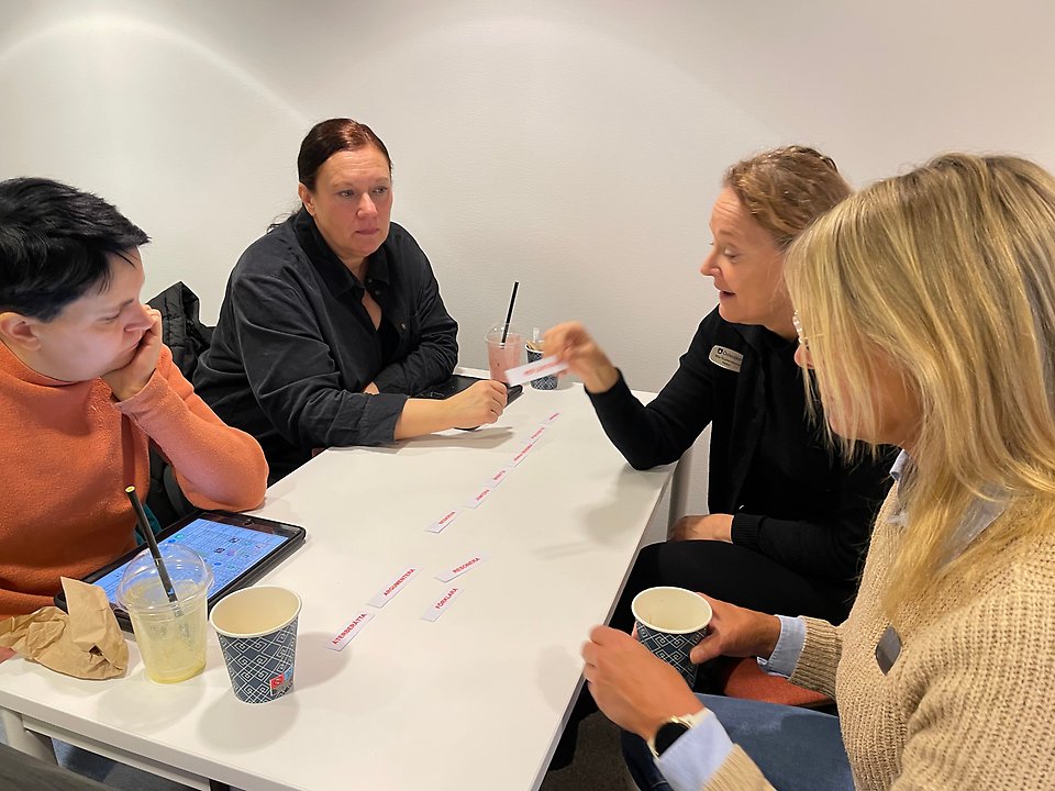 fyra personer diskuterar kring ord på kort