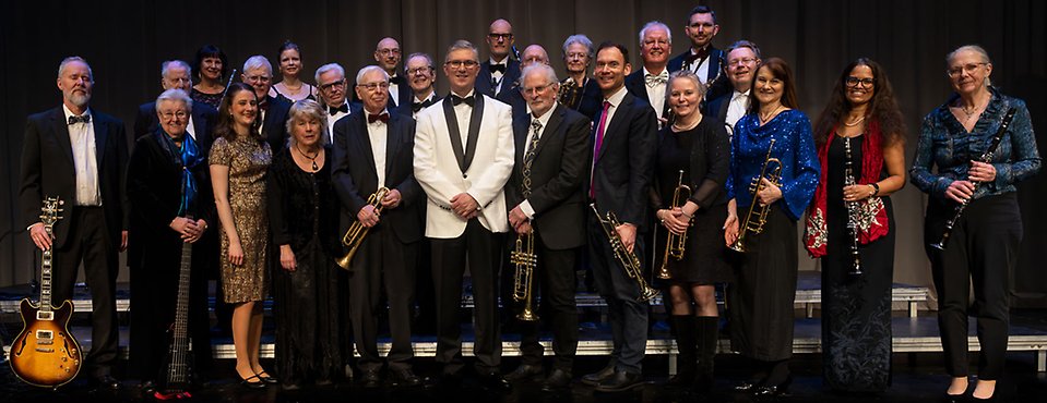 En gruppbild med en stor orkester. De är finklädda, kostym eller lång klänning.