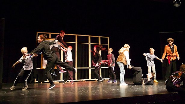 Bild en grupp barn och vuxna som virvlar runt och dansar.