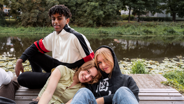 Två kvinnor som sitter bredvid varandra och åker buss samtidigt som de kollar ned i sina telefoner och ler.