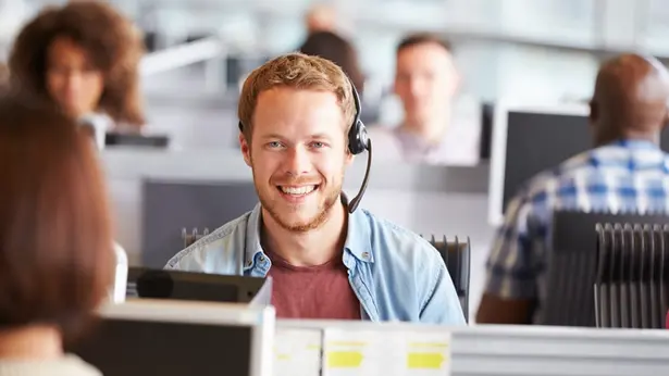 Man som sitter i ett call center och tittar i kameran.