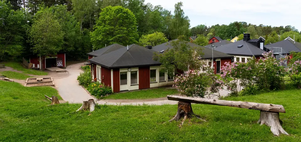 Bild på förskolan Båtstorp, röda enplans hus som sitter ihop i grönskande miljö