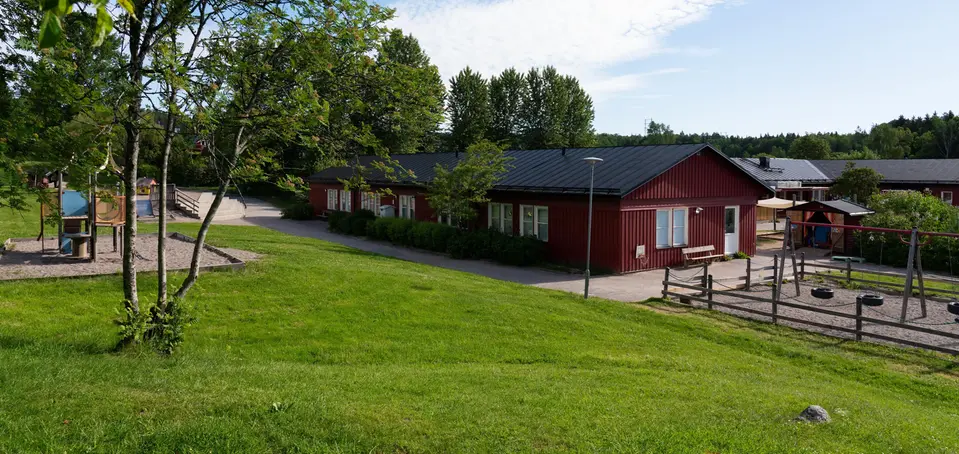 Bild på förskolan Kantarellen, röda enplans hus som sitter ihop i grönskande miljö