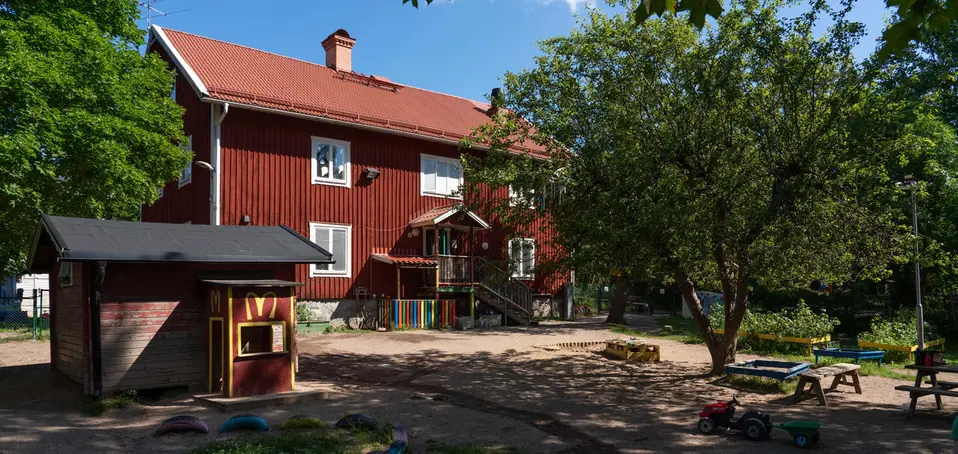 Bild på Ljusterö förskola, rött tvåplans hus i grönskande miljö