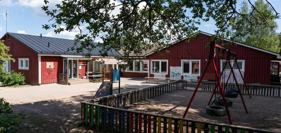 Bild på Söralids förskola, röda enplans hus som sitter ihop i grönskande miljö