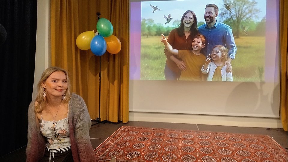 Kristina Kiviniemi istuu Österåkerin kirjaston lavalla, taustalla ilmapallot ja vapun aiheinen kuva